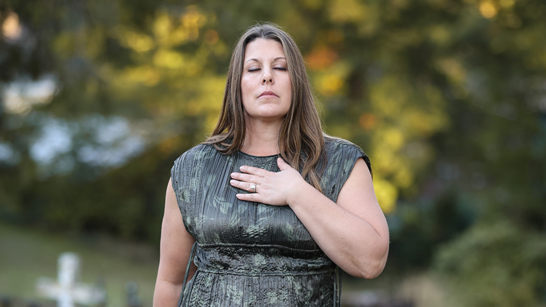 Amanda Smith standing outdoors with her eyes closed and hand over her heart, reflecting on overwhelm in sensitive people.